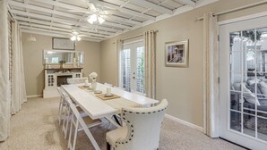 A dining area with a white table, chairs, and ceiling fans. There is a kitchen area with a window and a door leading outside. - 2 Mi to Dtwn: Charming Sandusky Getaway w/ Hot Tub (Sandusky)