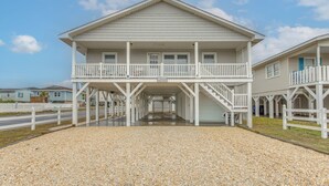 A two-story building with a balcony and a covered walkway. - Steps to Sand! Family Ocean Isle Beach Retreat (Ocean Isle Beach)