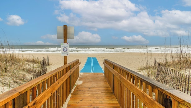 A wooden boardwalk leading to a beach with a blue path. - Steps to Sand! Family Ocean Isle Beach Retreat (Ocean Isle Beach)