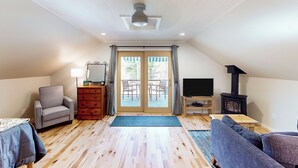 A cozy living room with a sofa, armchair, TV, and a fireplace. - Half-mile to Crystal Lake! Couples Retreat w/ Deck (Beulah)