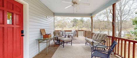 A covered porch with a red door, a ceiling fan, and outdoor furniture.