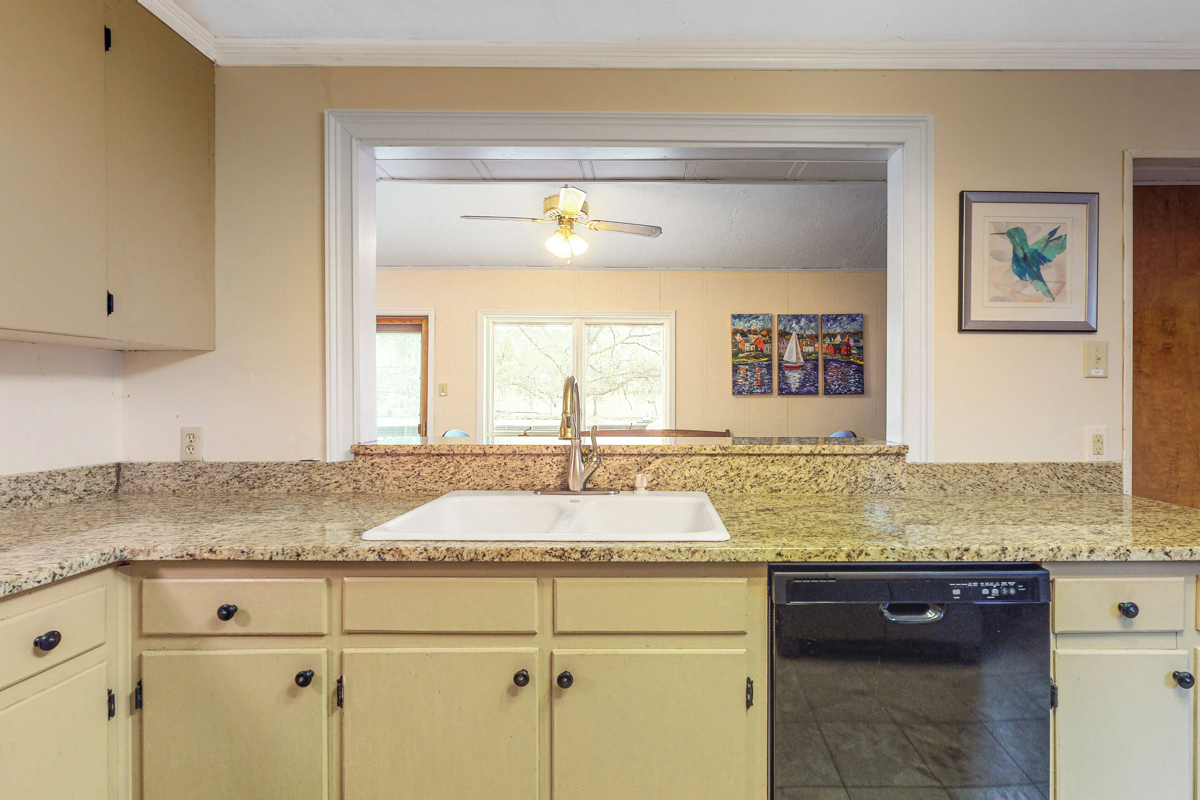 A kitchen with a granite countertop, a dishwasher, and a sink.