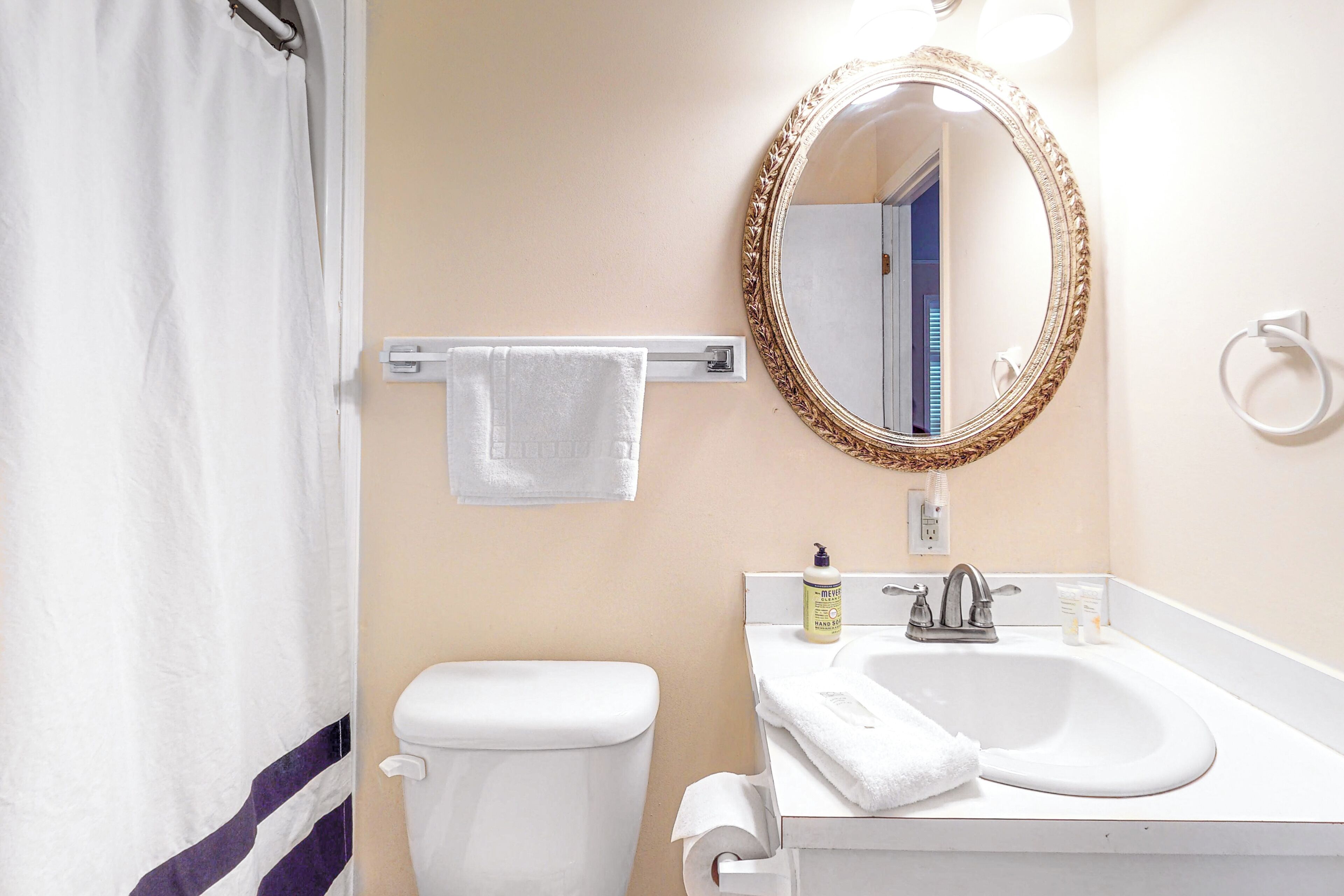 A bathroom with a toilet, sink, and mirror.