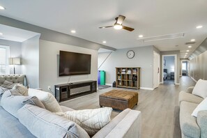 Ein geräumiges Wohnzimmer mit einem großen Flachbildfernseher, einem Deckenventilator und einem Bücherregal.