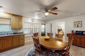 A dining area with a wooden table, chairs, a ceiling fan, and a kitchen in the background. - Fish, Boat & Hike! Kingston Home on Large Lot (Kingston)