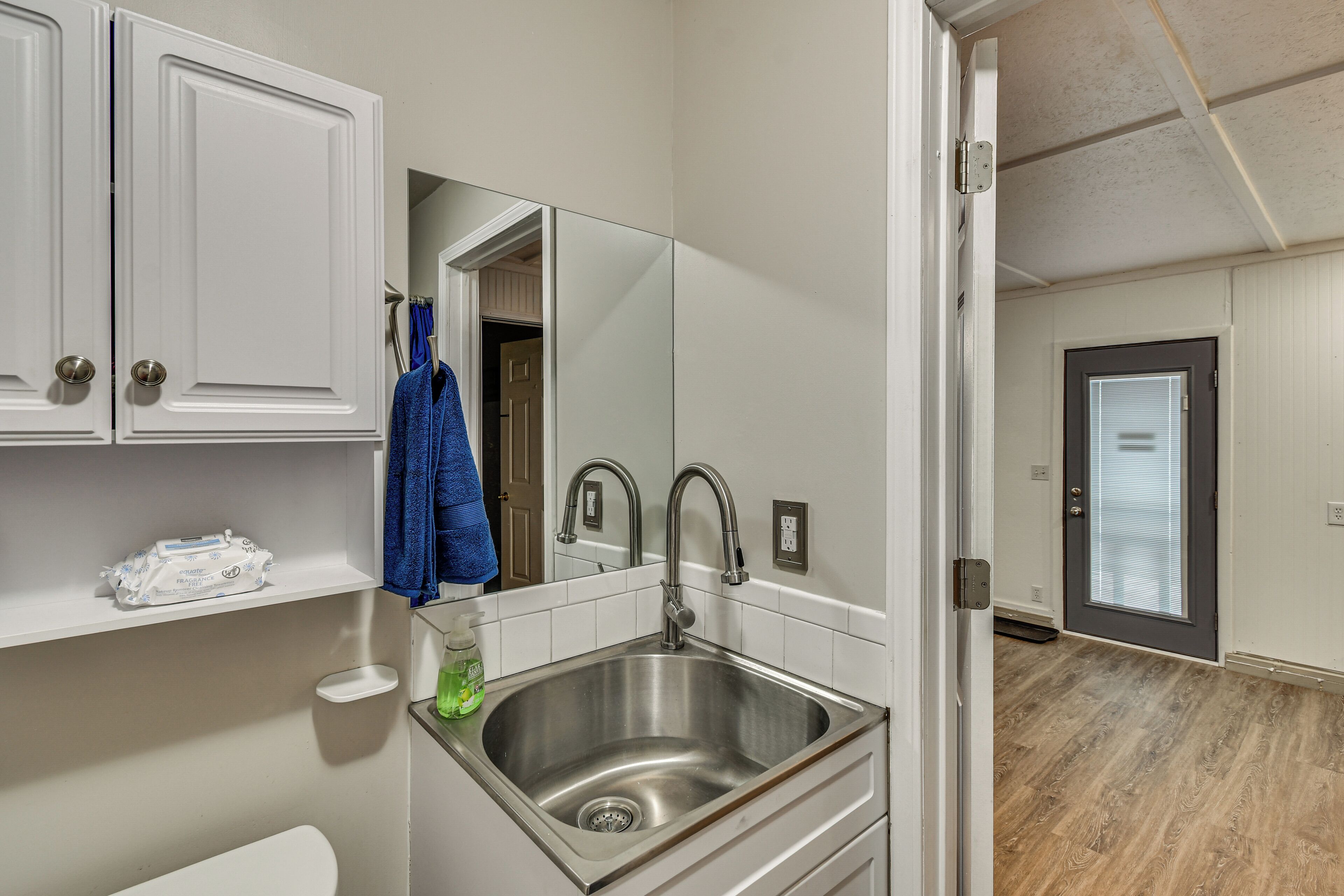 Une salle de bain moderne avec un évier en acier inoxydable, des meubles blancs et un miroir.
