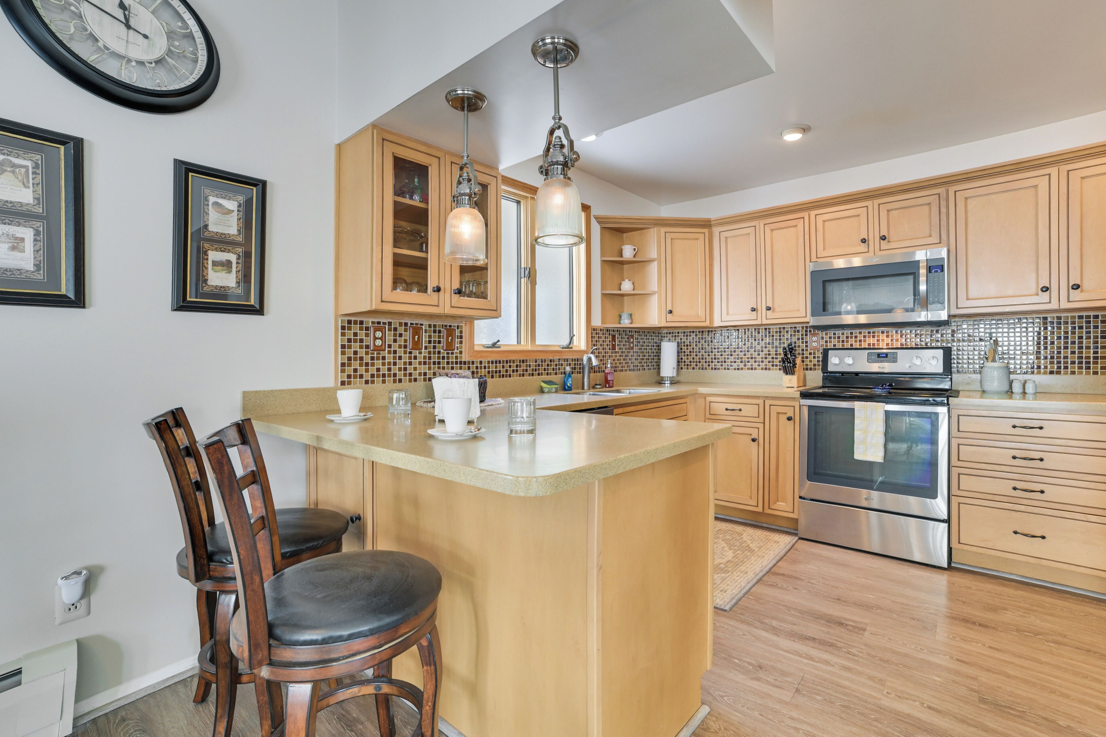 A kitchen with wooden cabinets, a large island, stainless steel appliances, and pendant lighting.