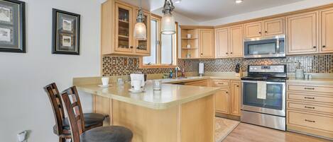 A kitchen with wooden cabinets, a large island, stainless steel appliances, and pendant lighting.