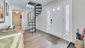 Un couloir doté d’un plancher en bois, d’un escalier en colimaçon et d’une porte ornée de vitraux.