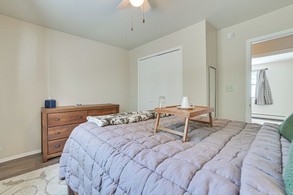 A bedroom with a bed, a dresser, a nightstand, and a door. - Porch + Views: Waterfront Home on Houghton Lake! (Houghton Lake)