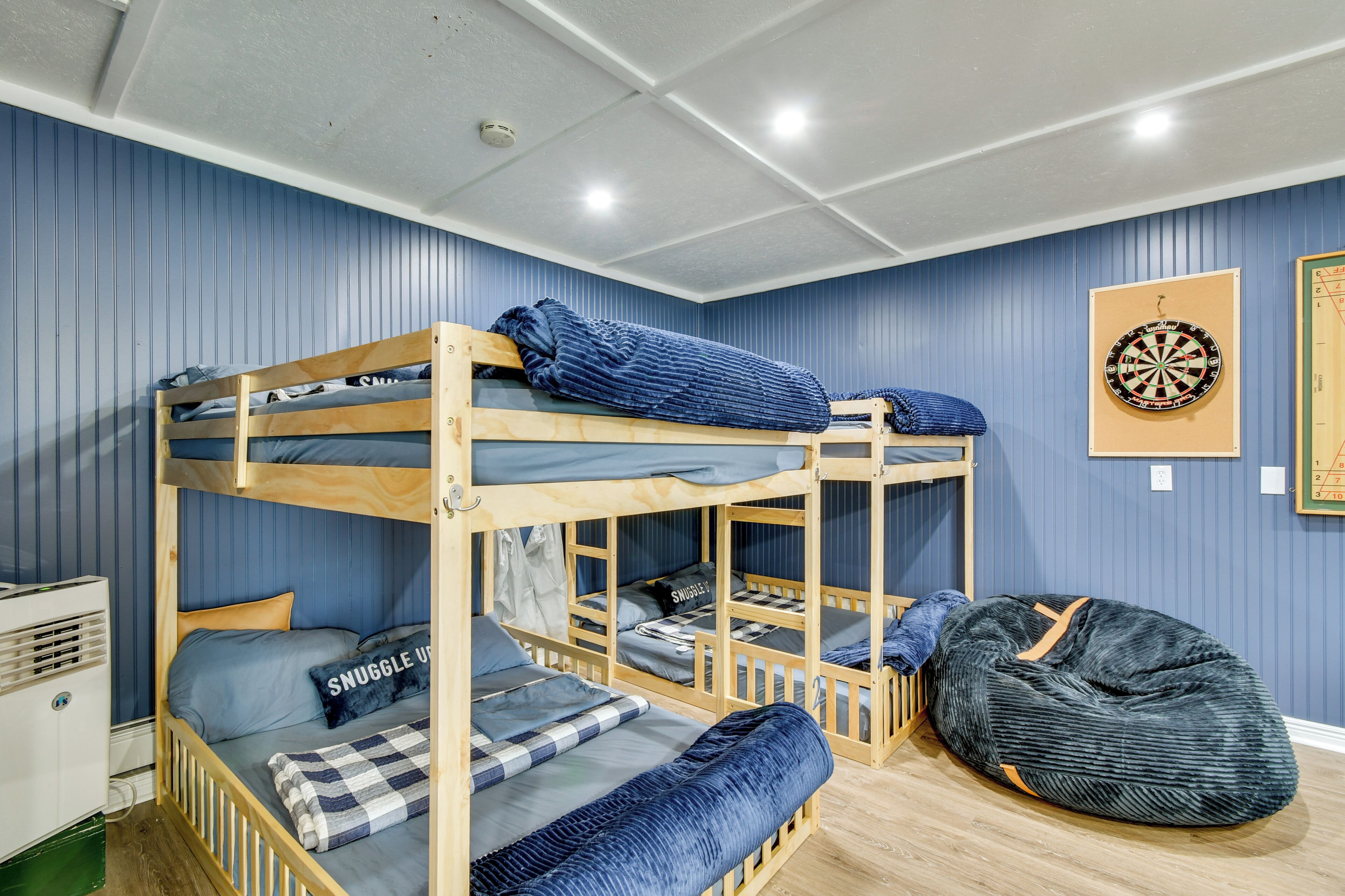 A bunk bed room with a bean bag, a dartboard, and a small heater.