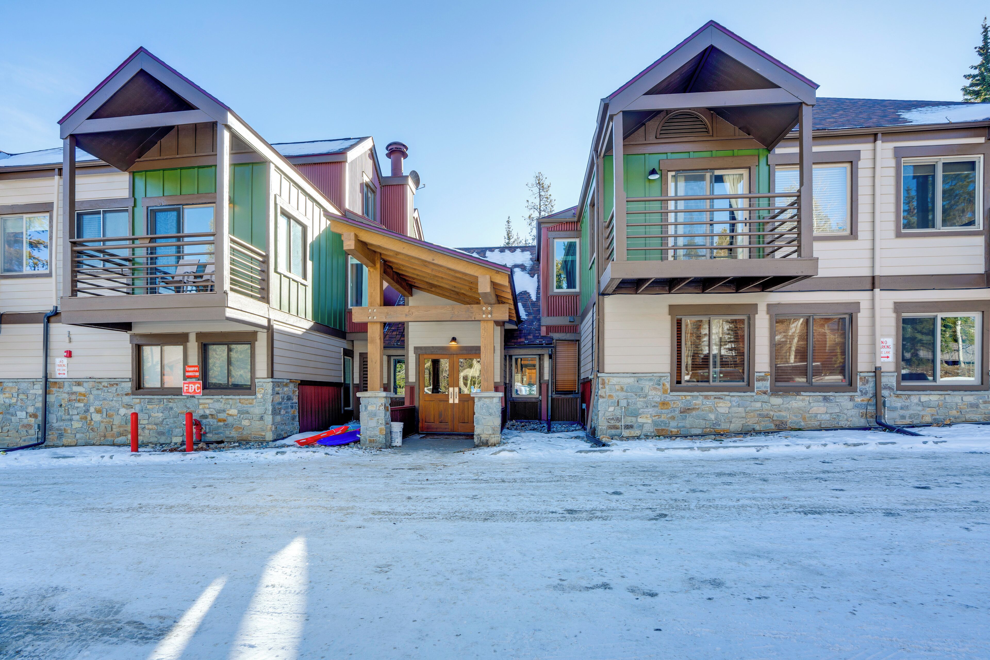 A row of multi-story buildings with balconies, stone foundations, and a snow-covered ground.