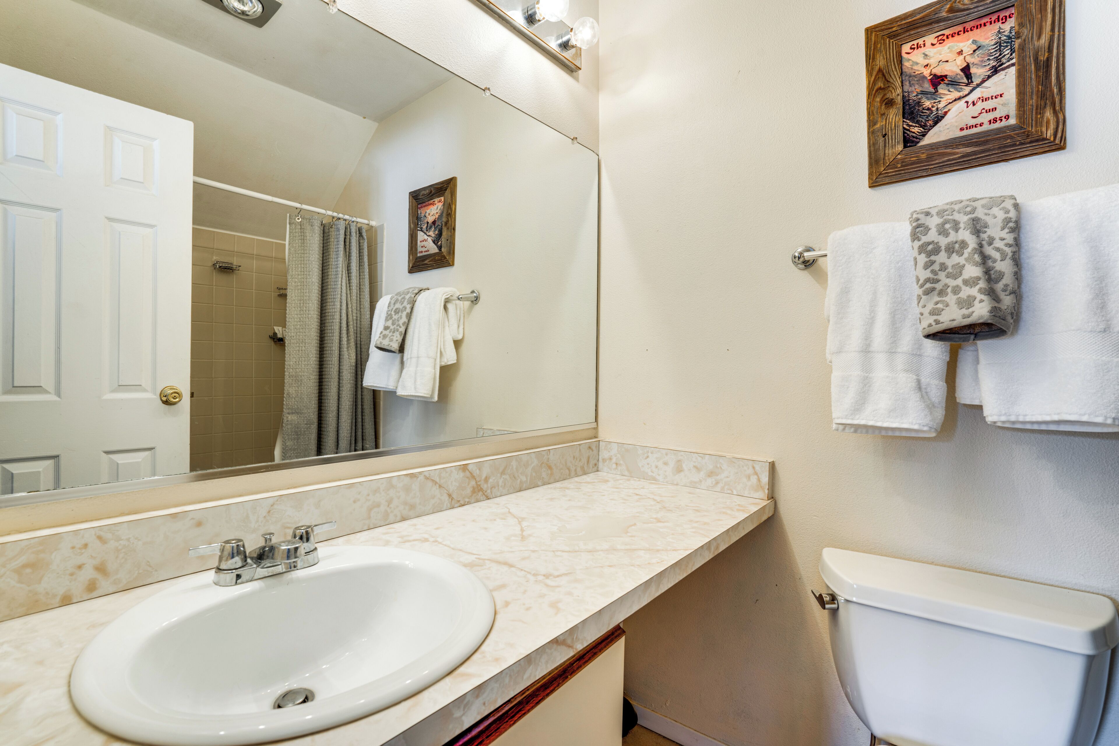 Een badkamer met een wit wastafel, toilet, douche en een handdoekrek met meerdere handdoeken.