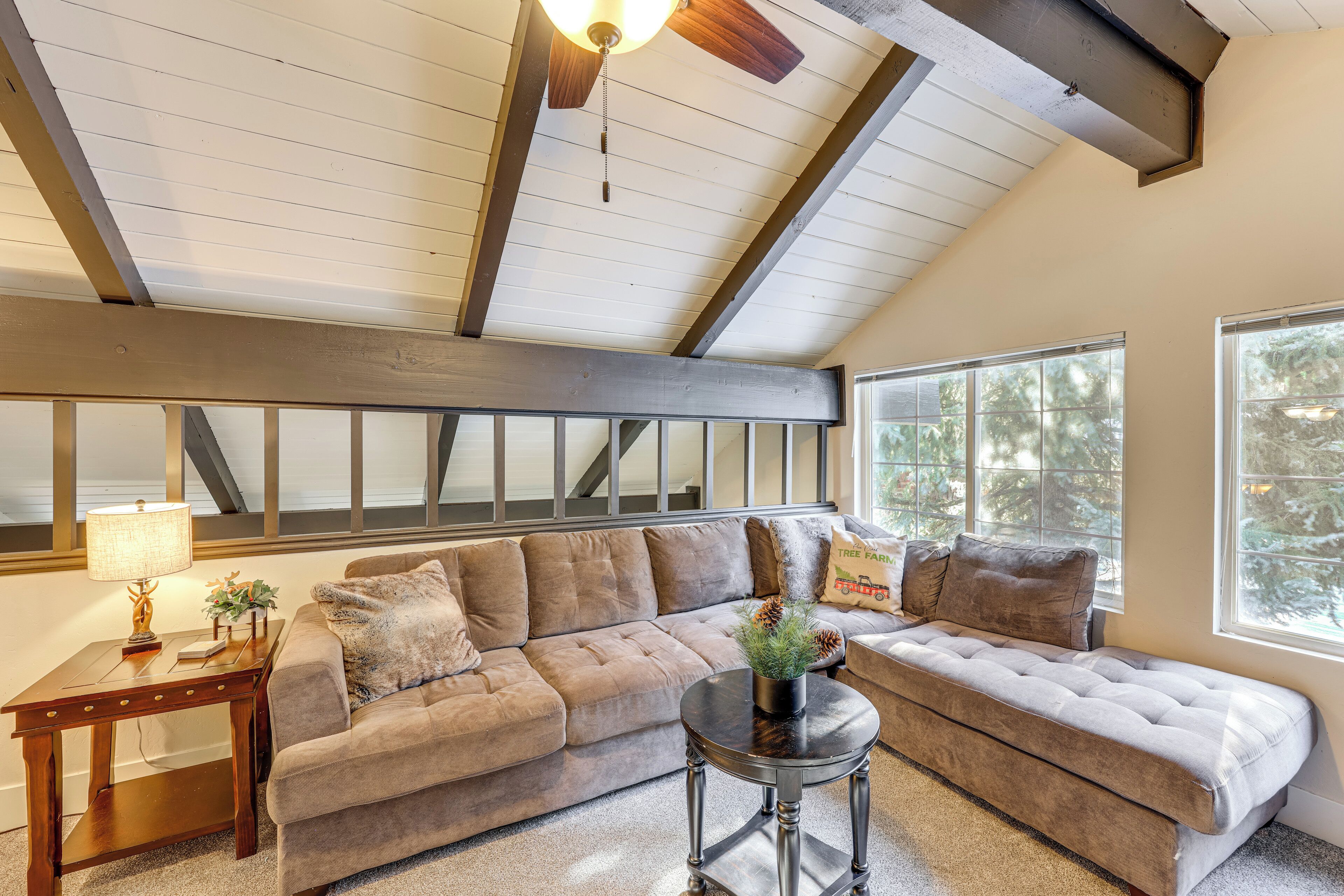 A cozy living room with a sectional sofa, a small side table, and a ceiling fan.