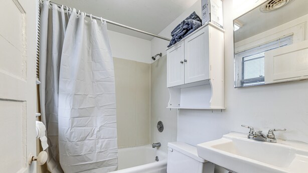 A bathroom with a bathtub, toilet, sink, and a shower curtain. - Work & Study: Binghamton Apt 2 Mi to Downtown (Binghamton)