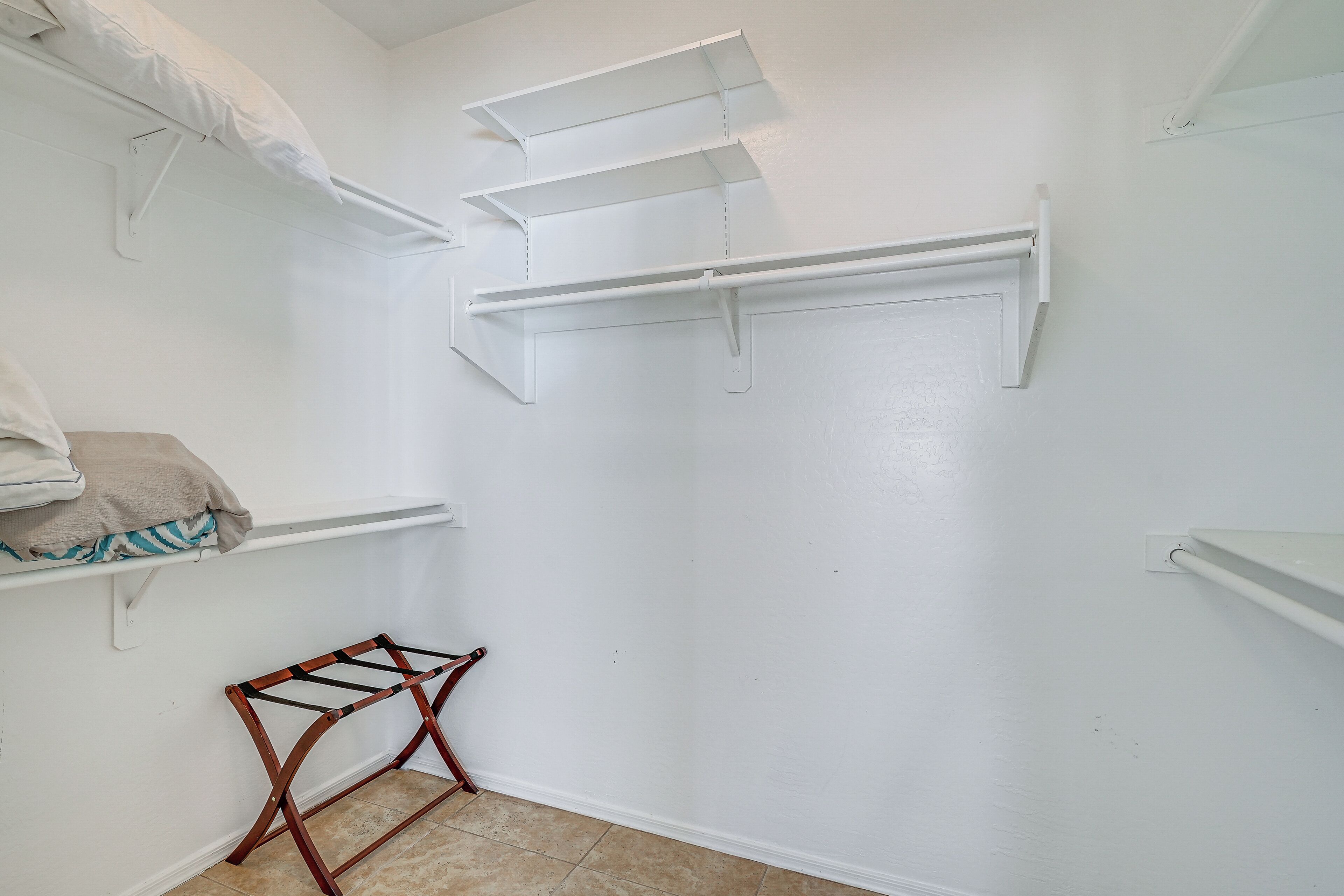 A laundry room with white walls, a drying rack, and three shelves.