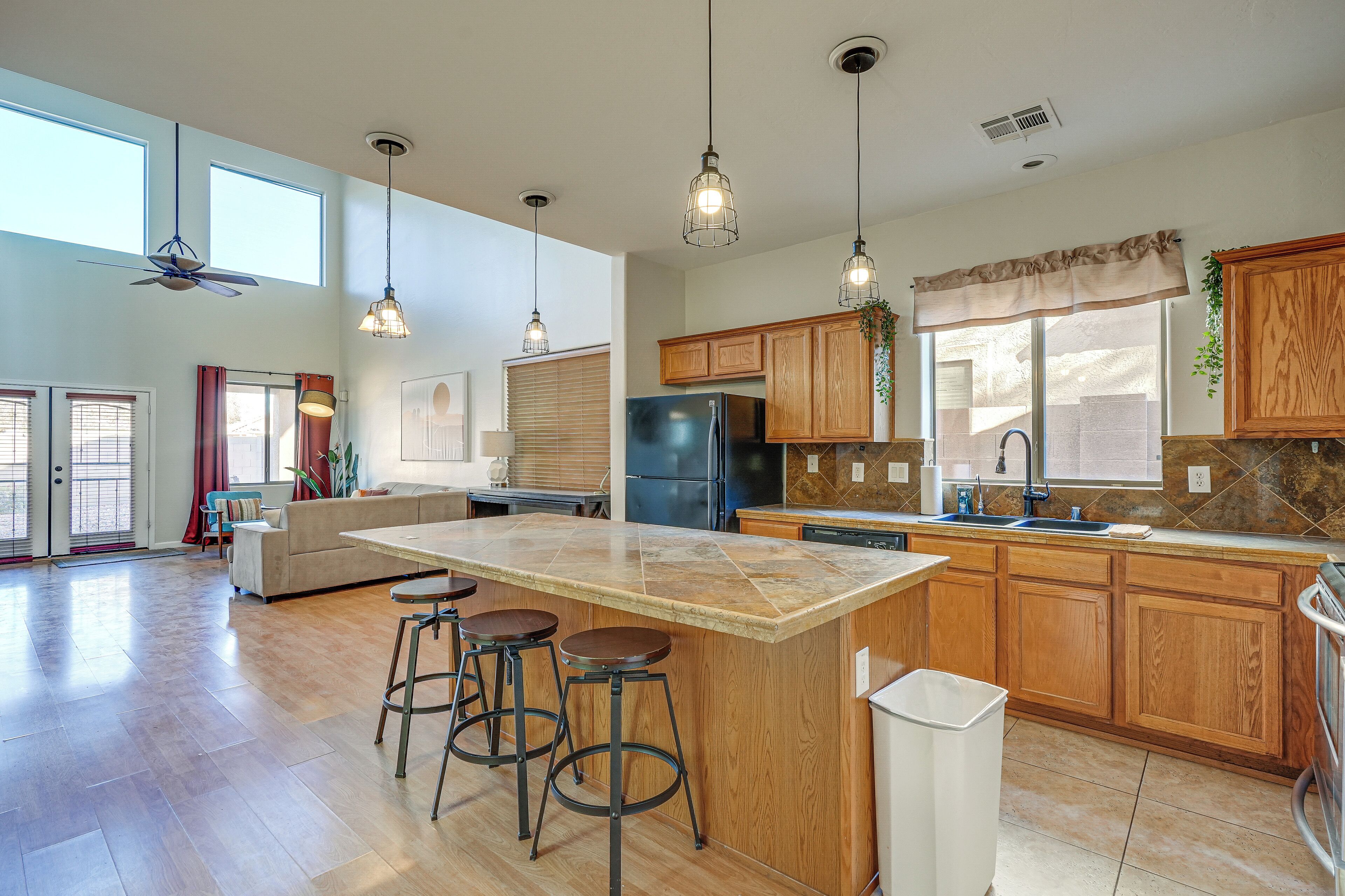 A spacious kitchen with a large island, wooden cabinets, and pendant lighting.