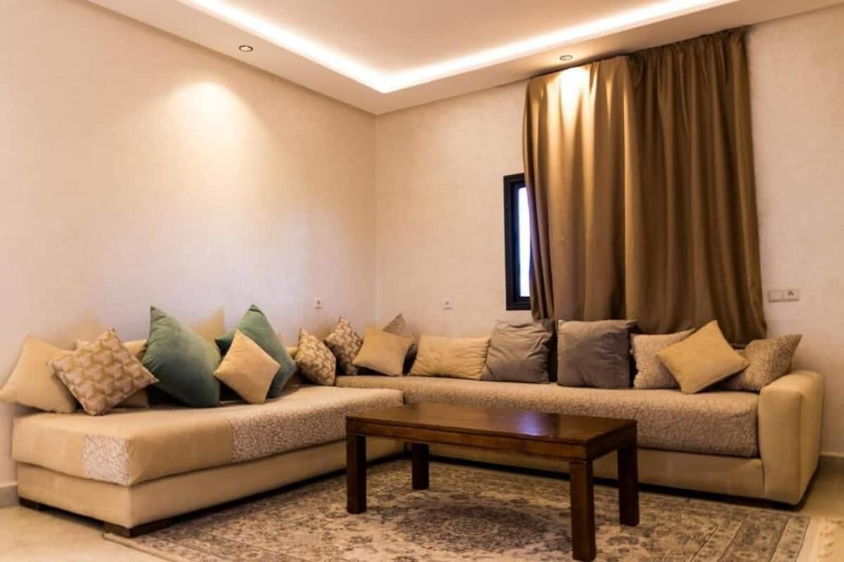 A living room with a beige sofa, a wooden coffee table, and a patterned rug.