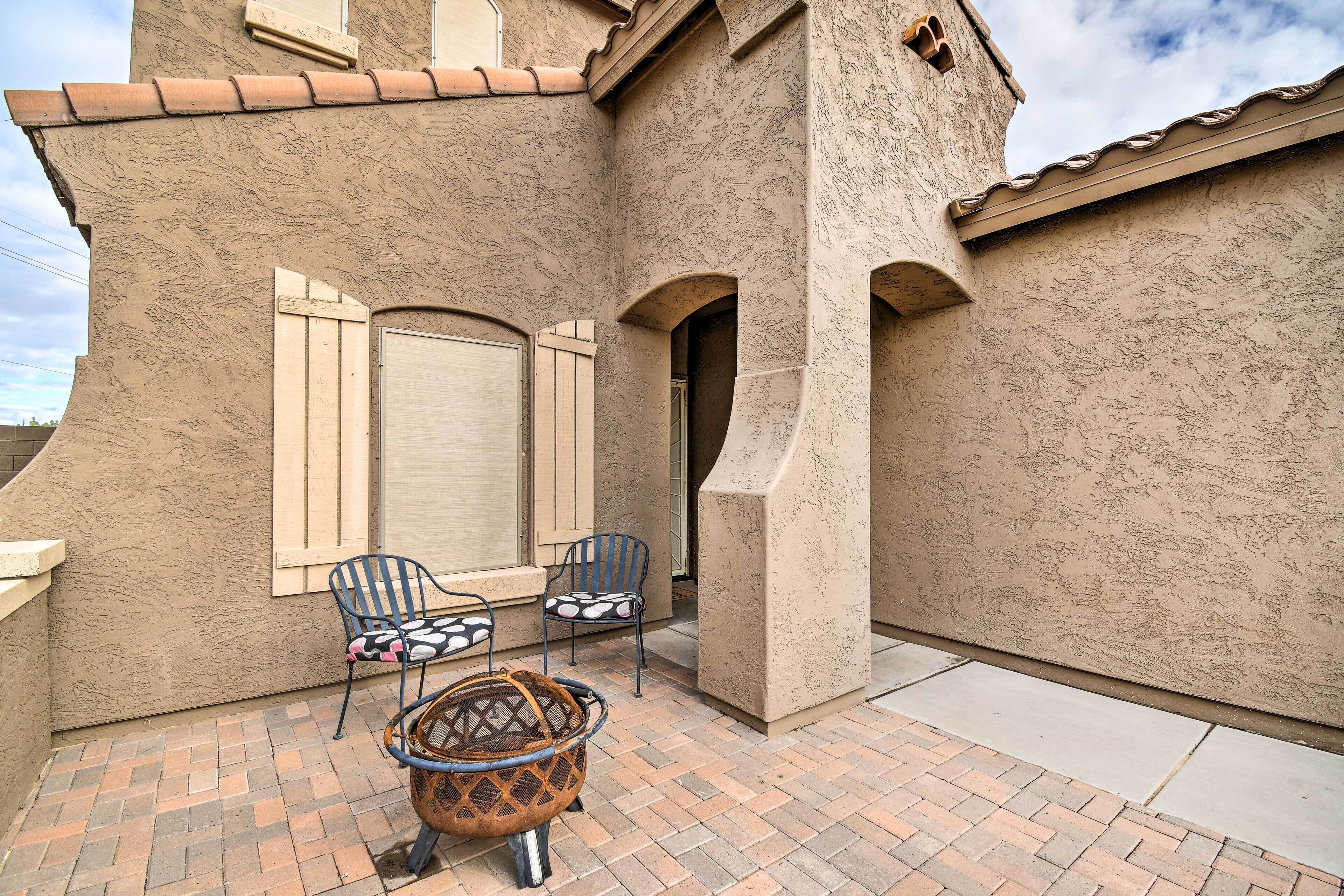An outdoor patio with two chairs, a basket, and a door.