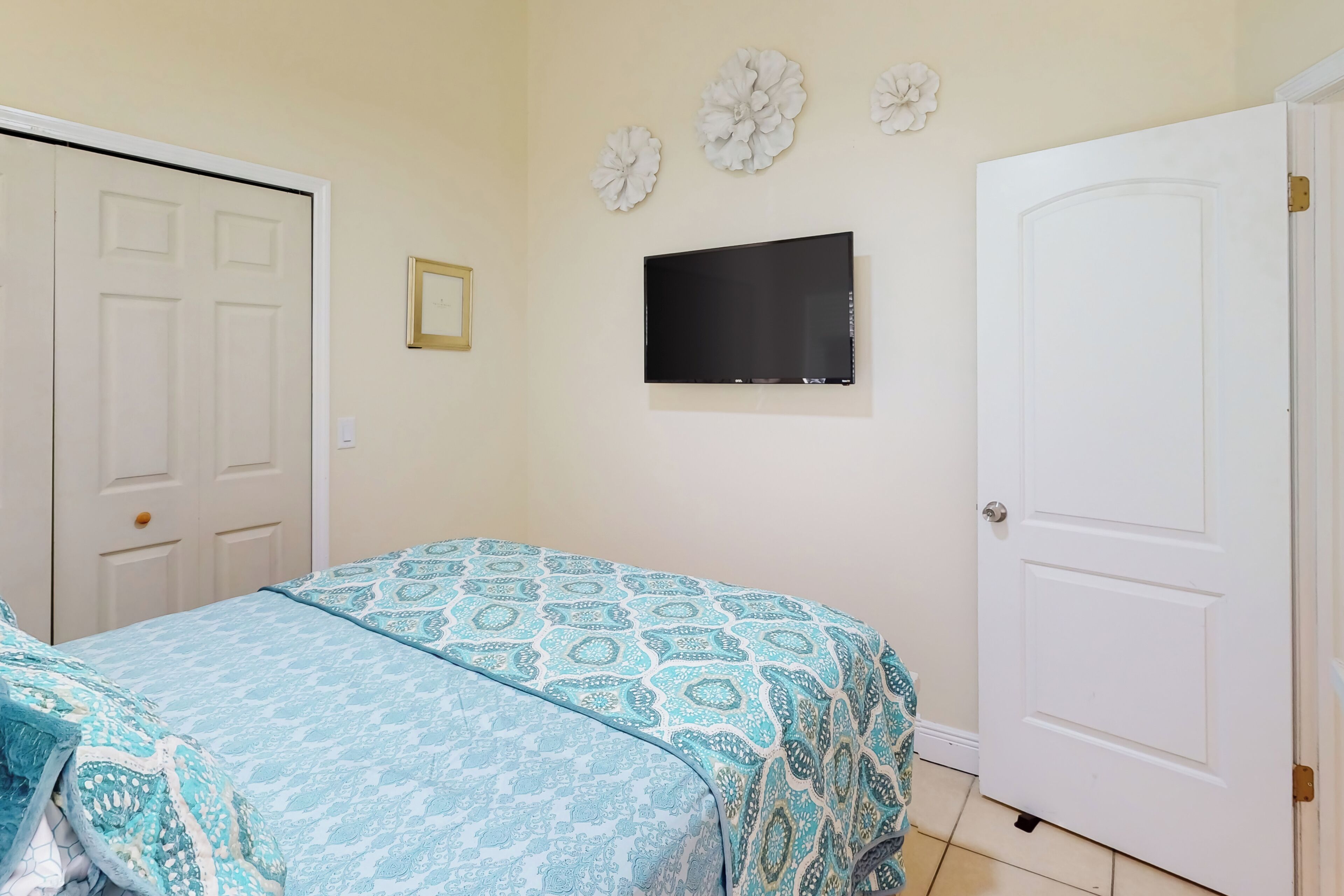 A bedroom with a bed, a TV, and a door.