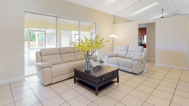 Un salón amplio con un sofá color crema, un sillón blanco y una mesa de centro de madera oscura.