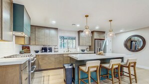 Cozinha moderna com ilha central, banquetas e iluminação pendente.