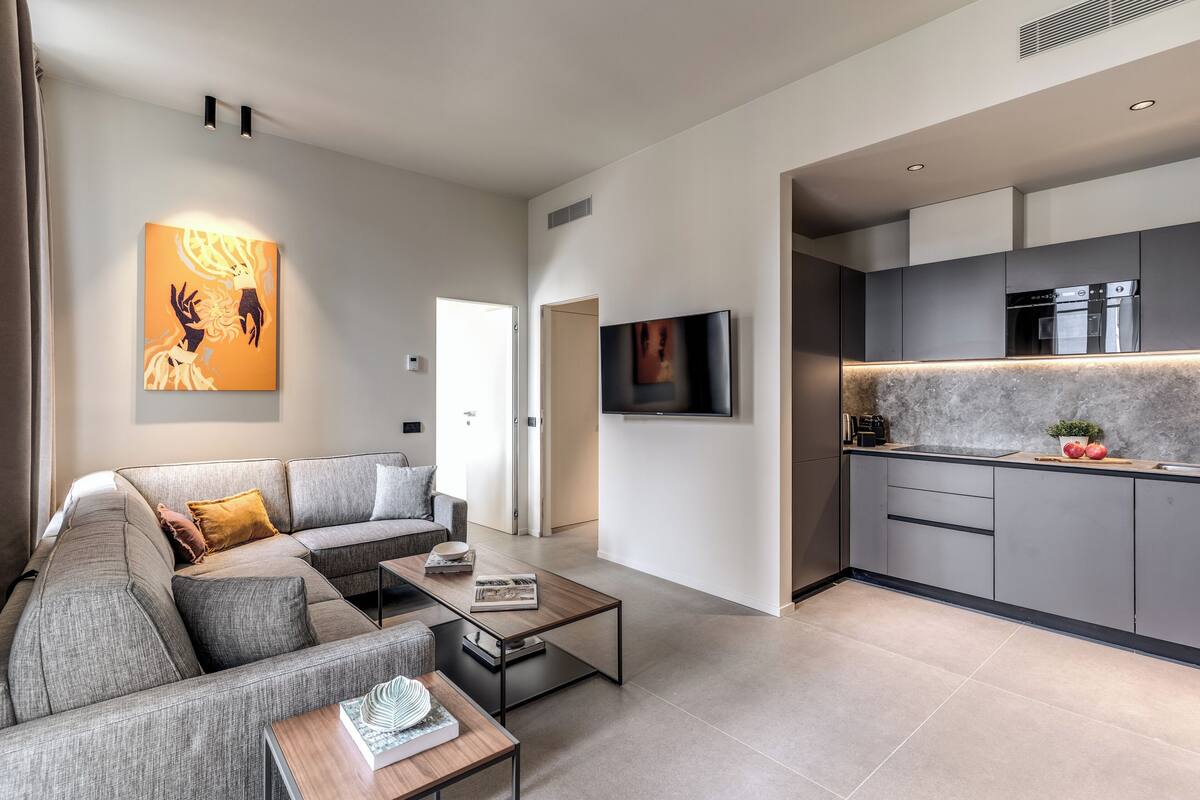 A modern living room with a grey sofa, a coffee table, and a flat-screen TV.