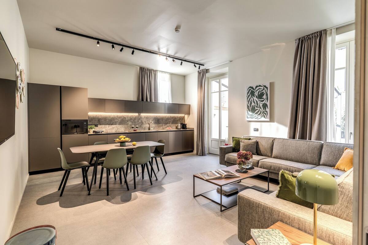 A modern living space with a dining area, kitchen, and seating area.