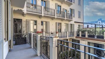 A multi-story building with balconies, a gated entrance, and a clear sky.