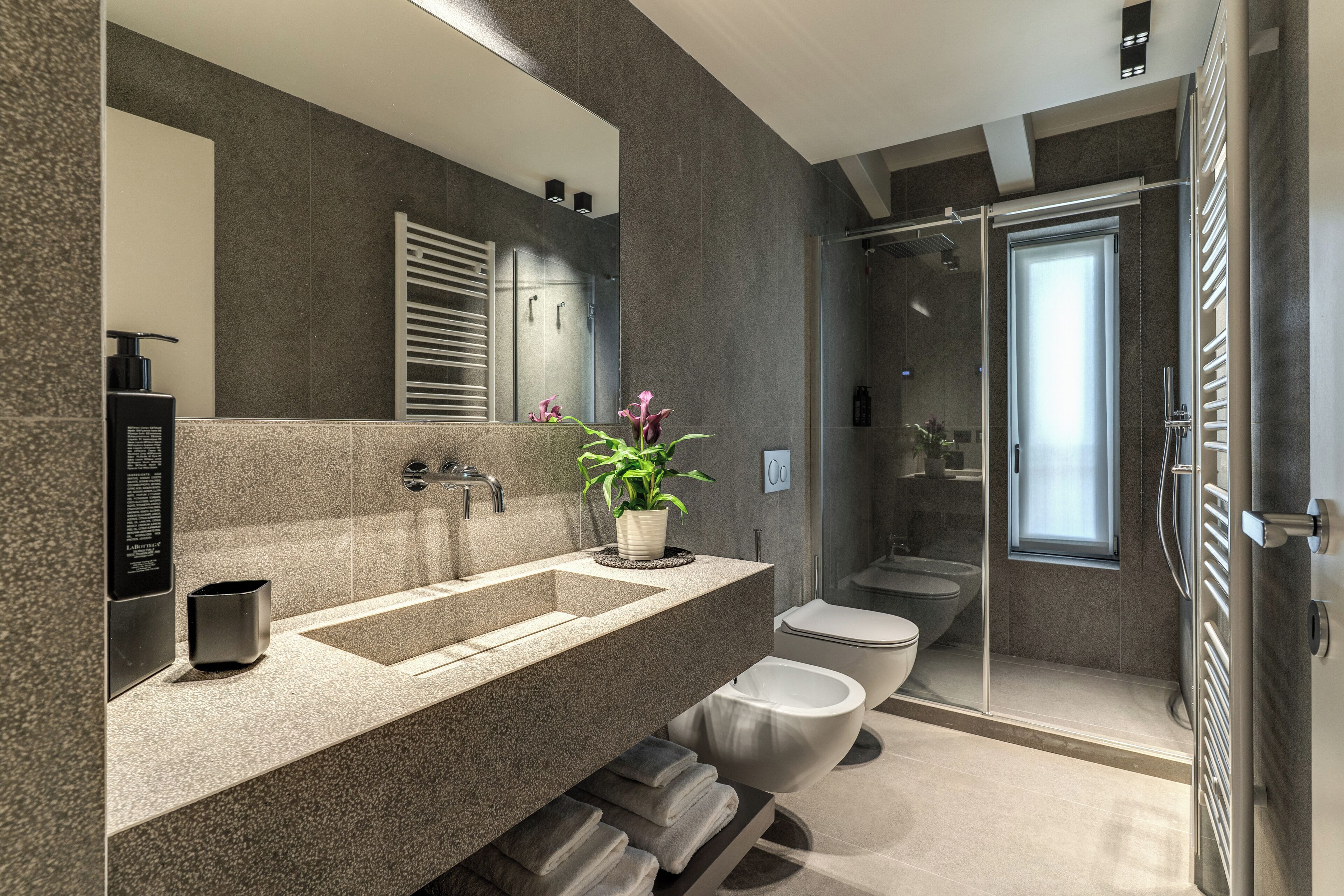 A modern bathroom with a large mirror, a sink, a toilet, and a shower area.