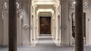 A grand hallway with ornate columns and a wooden door at the end. - Seety Spartaco (Milan)