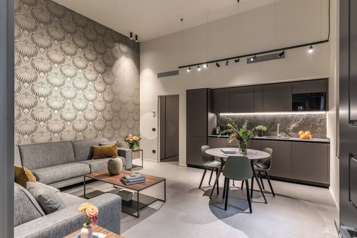 A modern living room with a grey sofa, a coffee table, and a dining area with a round table and chairs.