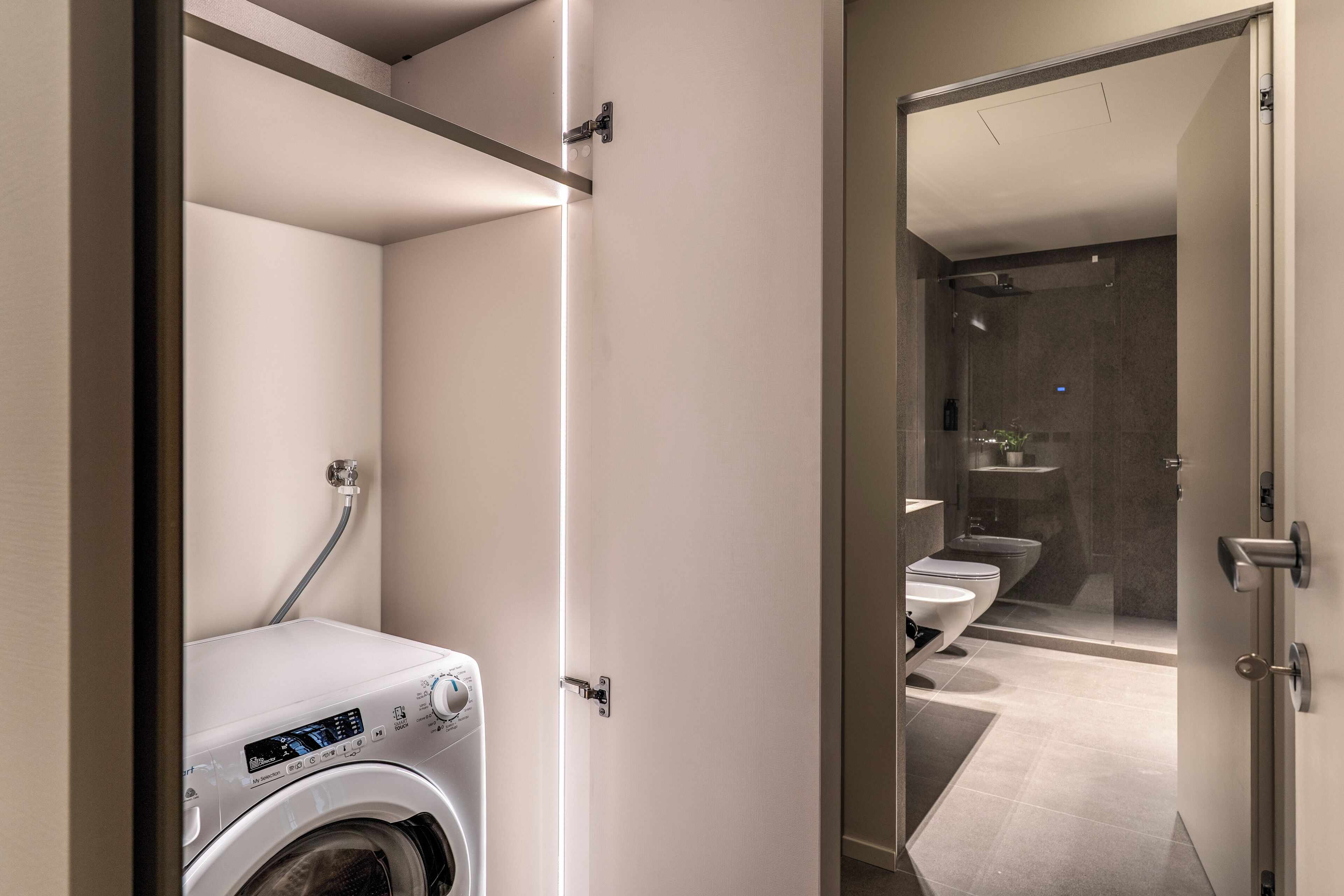 A modern bathroom with a washing machine, a toilet, and a shower area.