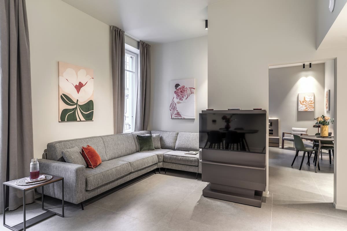 A modern living room with a grey sectional sofa, a small side table, and artwork on the walls.