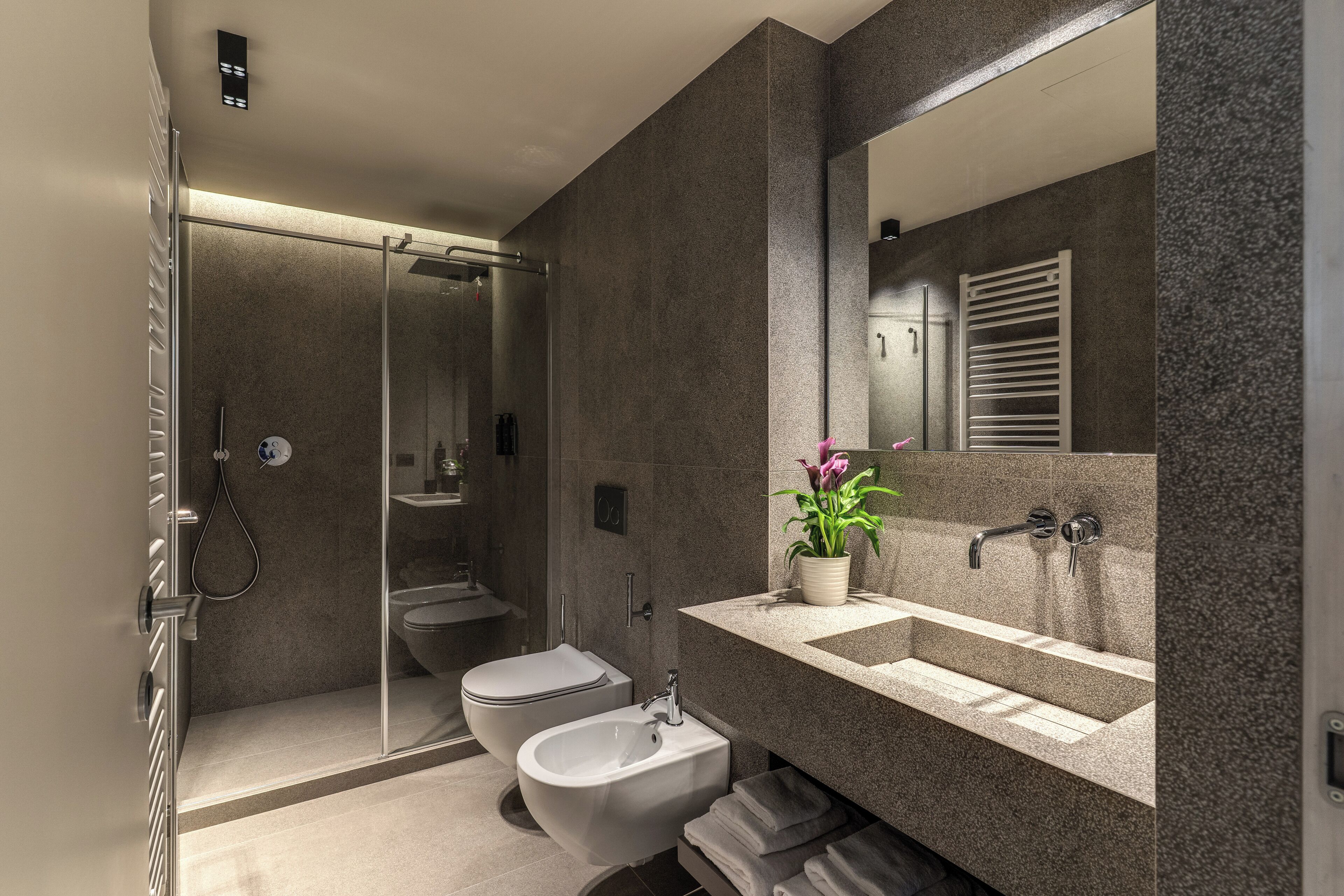 Ein modernes Badezimmer mit einer Duschkabine, einem Bidet, einem Waschbecken und einem Spiegel.