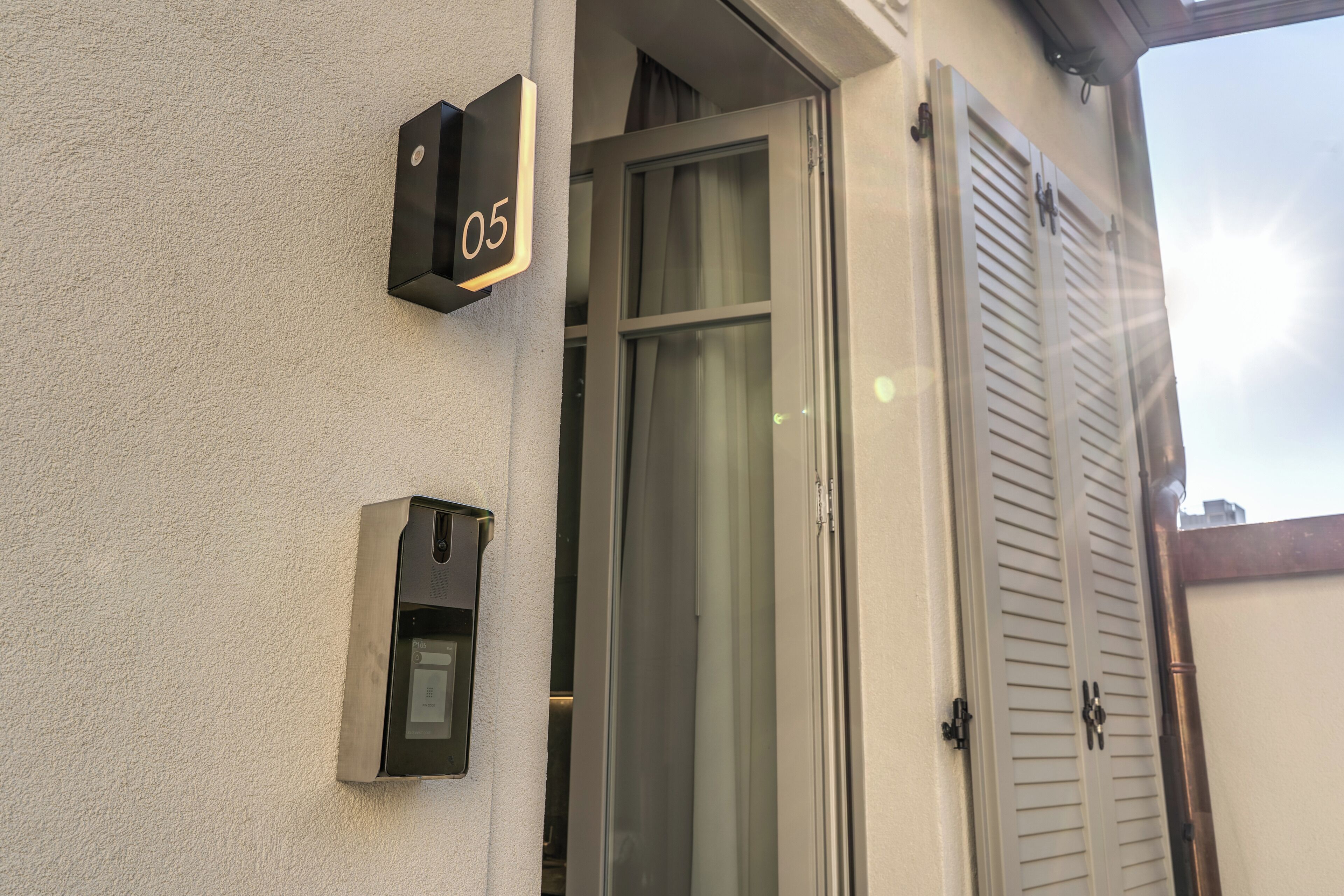 A building entrance with a door, a window with curtains, and a wall-mounted mailbox.