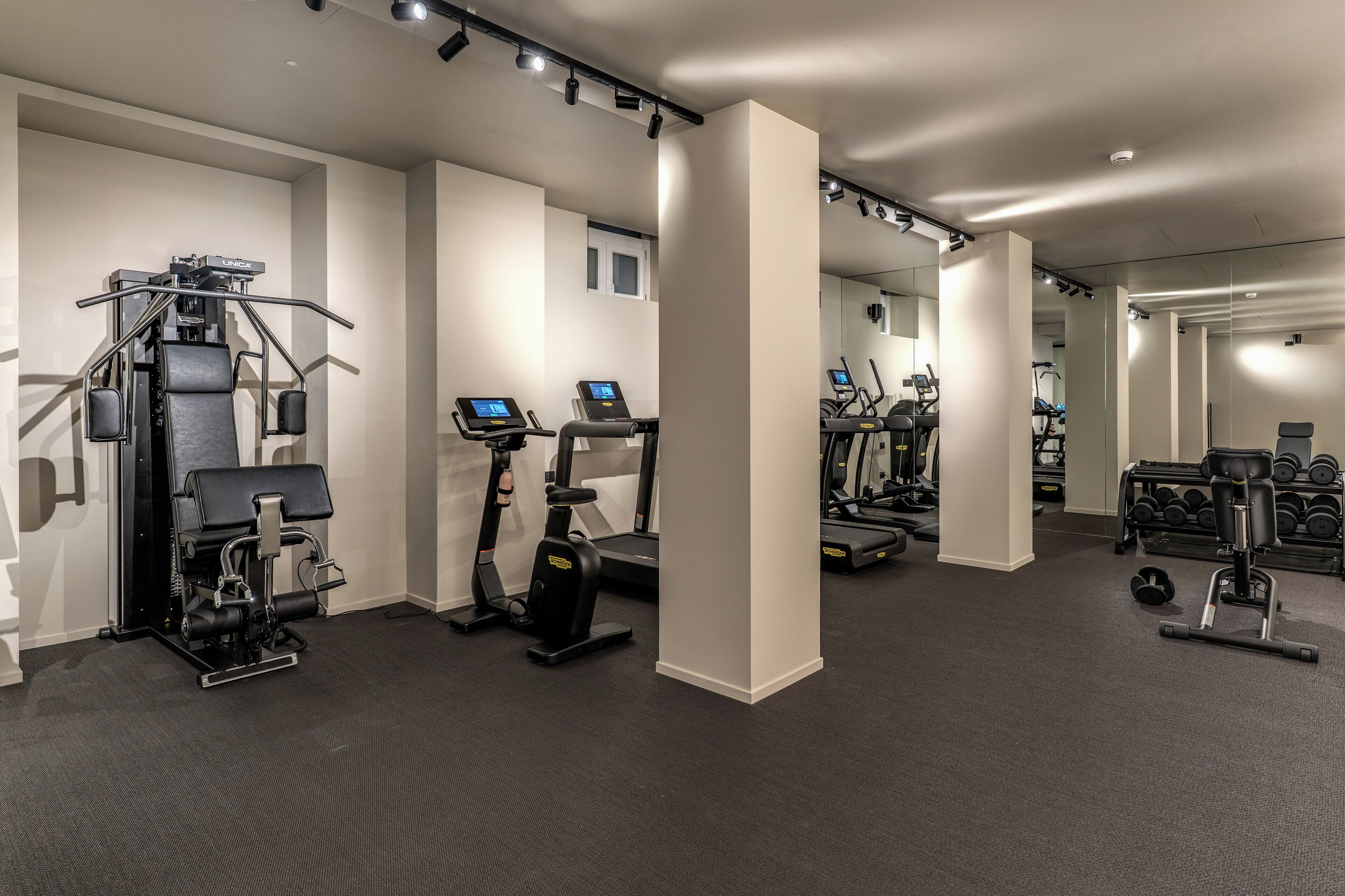Un gimnasio moderno con diversos equipos de ejercicio, incluyendo cintas de correr, elípticas y máquinas de pesas.