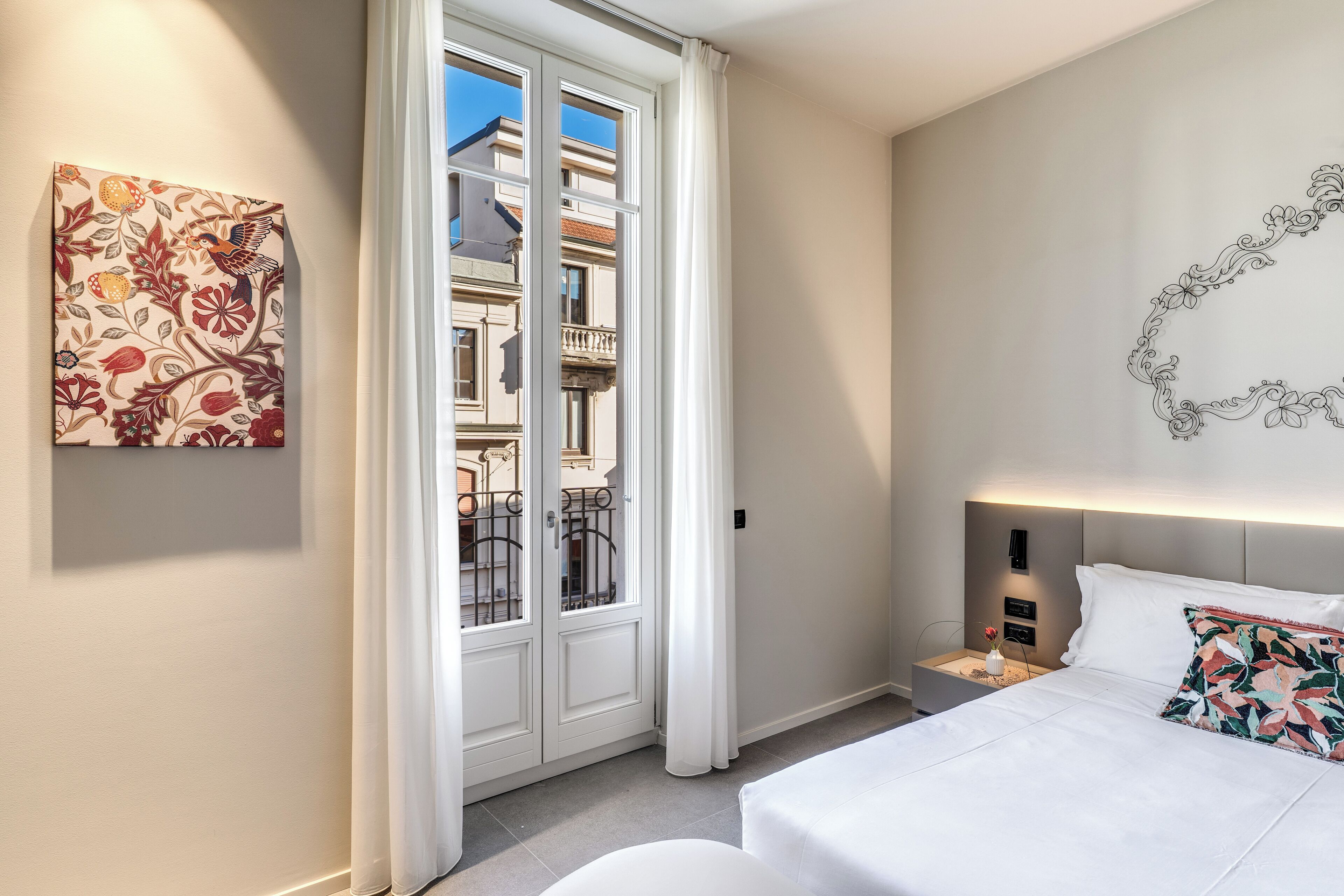 A bedroom with a bed, a nightstand, a wall-mounted artwork, and a view through a door.