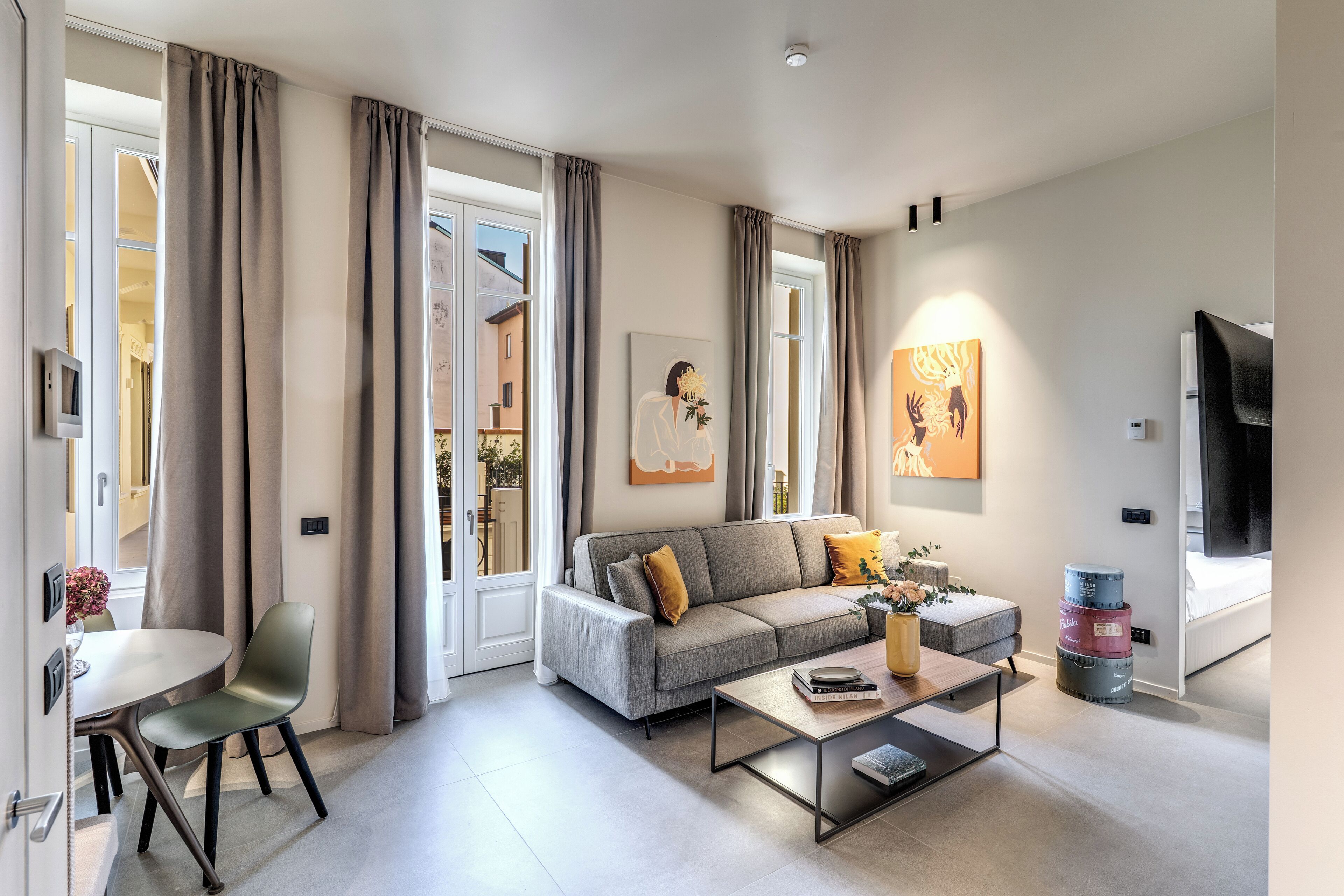 A modern living room with a grey sofa, a coffee table, and a dining area with a chair and table.