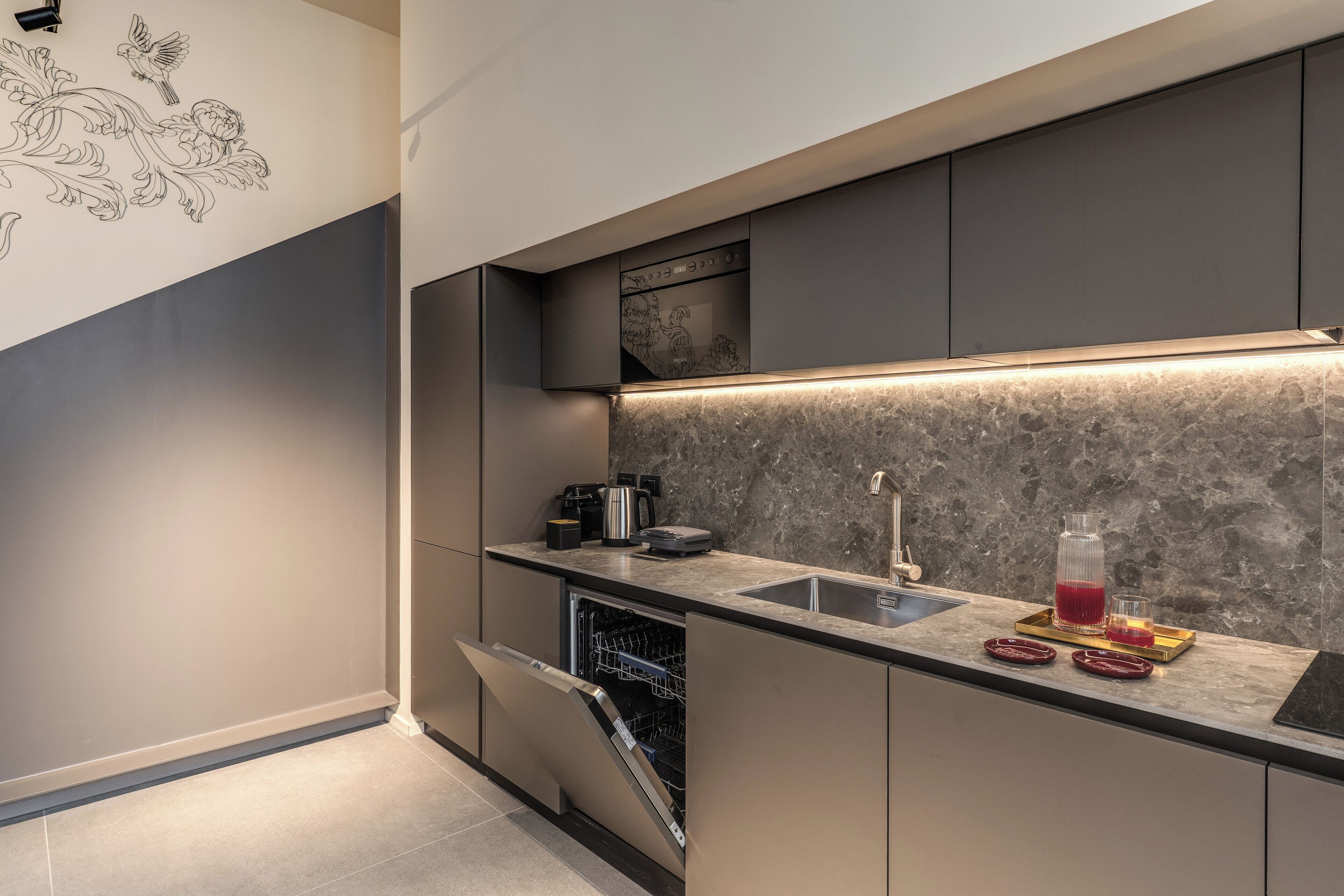 A modern kitchen with a built-in dishwasher, a marble backsplash, and a sleek countertop.