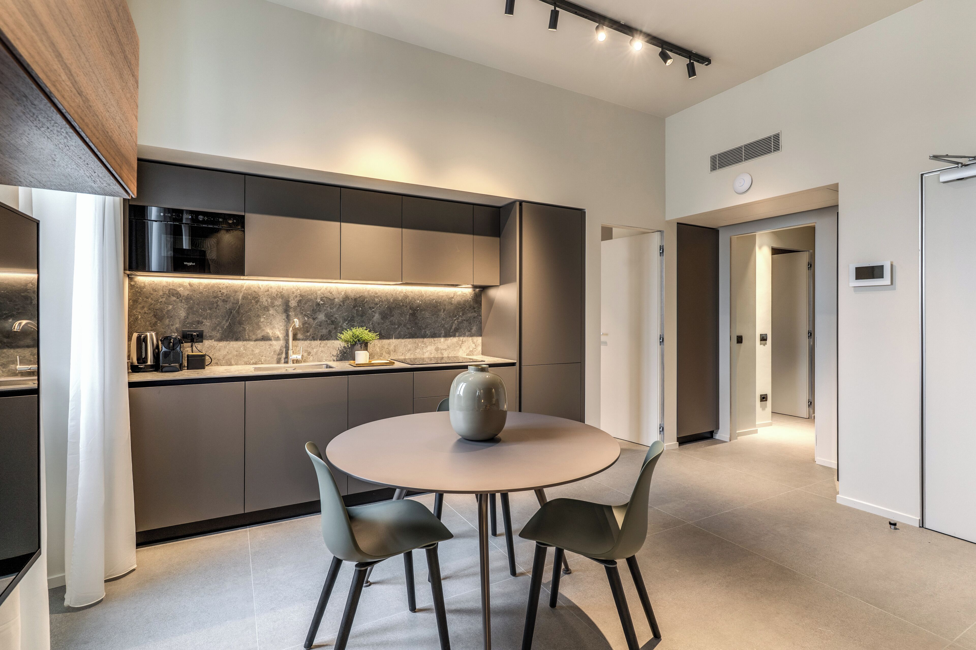 Een moderne keuken met een ronde eettafel, inbouwapparatuur en een minimalistisch design.