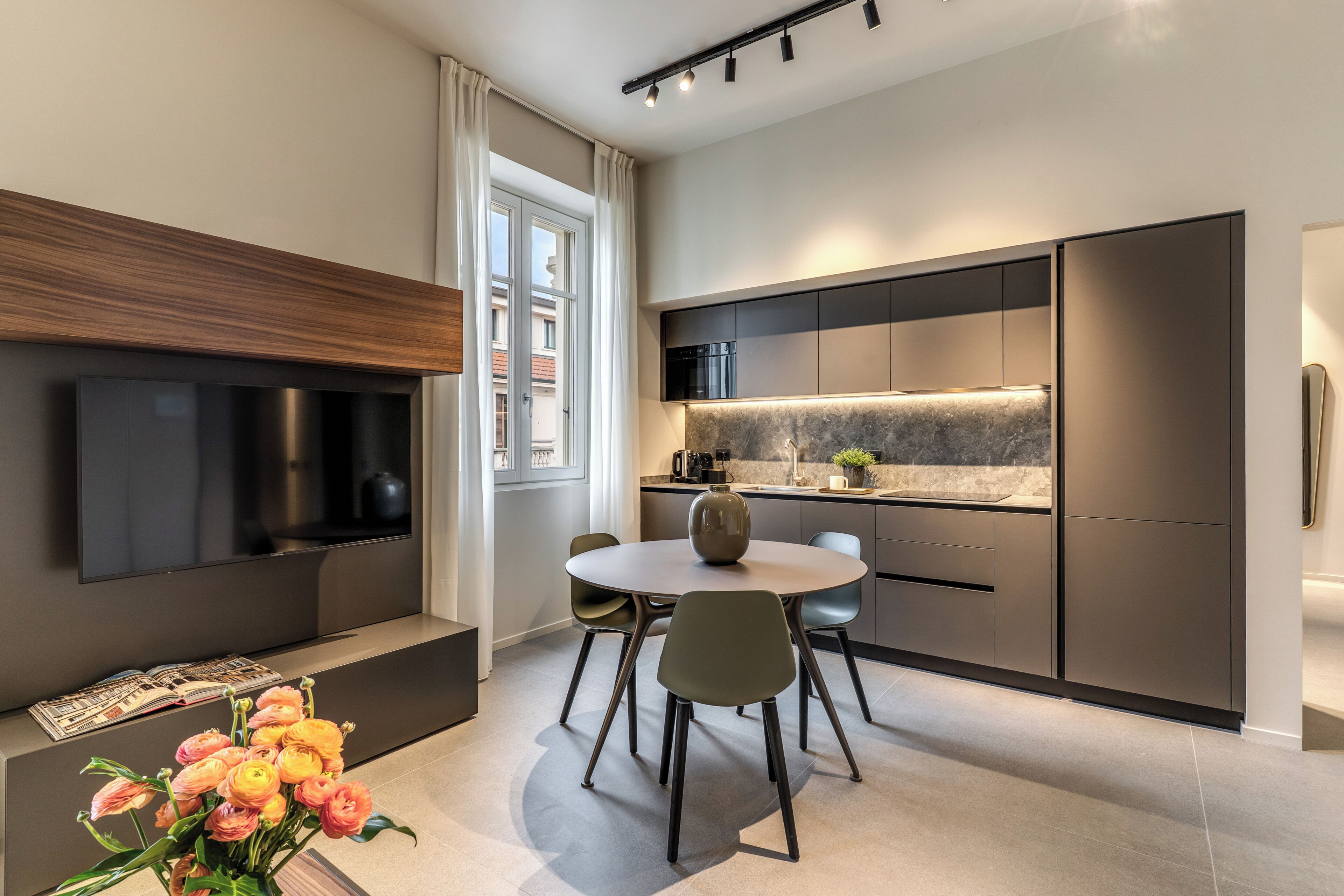 Een moderne keuken met een eethoek, inbouwapparatuur en een flatscreen-tv.