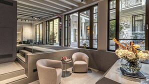 A modern hotel lobby with a seating area, a reception desk, and large windows offering views of the street. - Seety Spartaco (Milan)