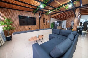 Un salón moderno con un sofá modular, una mesa de centro de madera y un televisor de pantalla plana montado en una pared de madera.