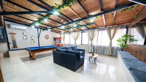 Amplia habitación con mesa de billar, sofás y un soporte para billares.