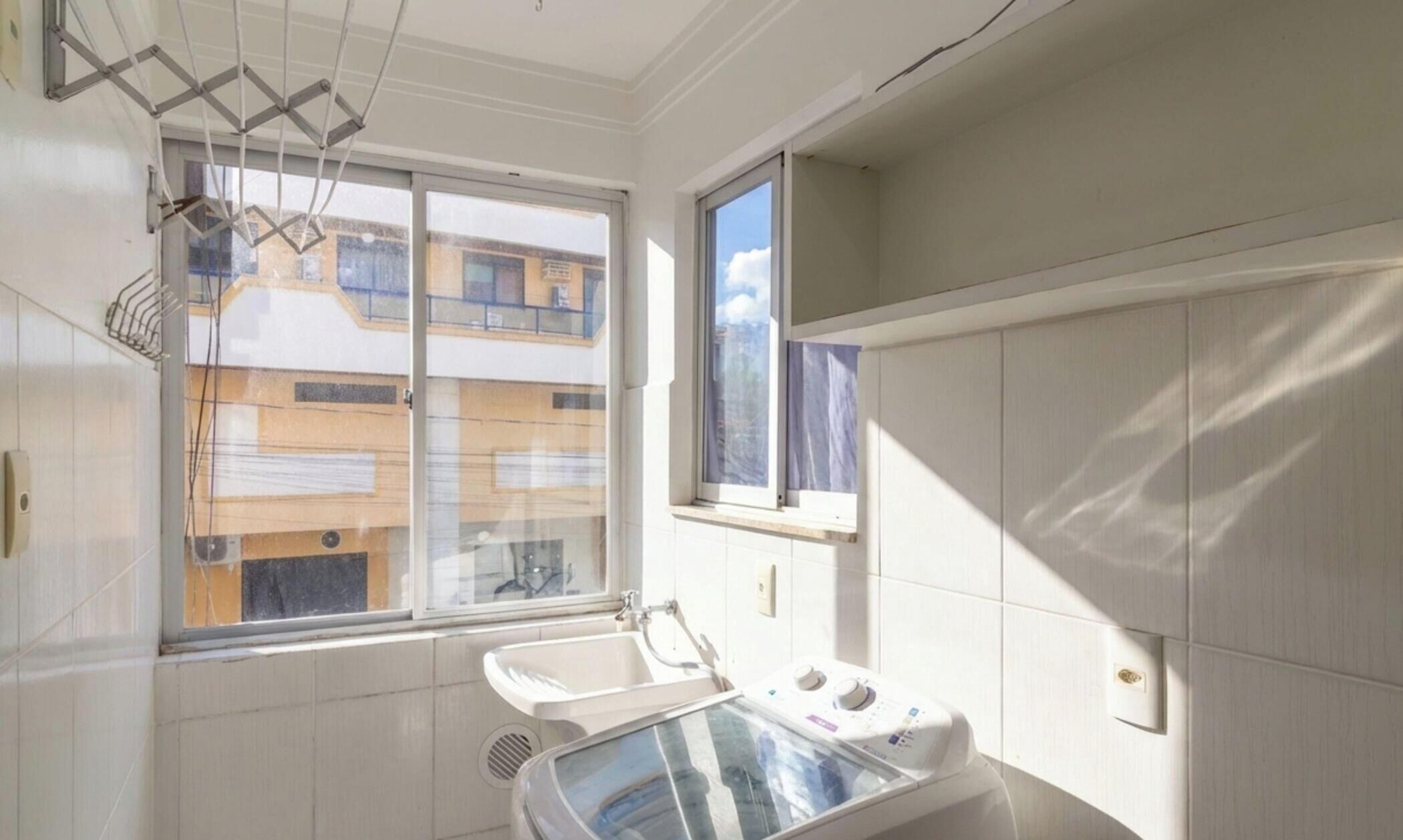 A bathroom with a window, a sink, and a shower.