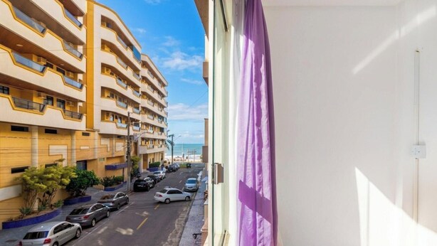 Un immeuble à plusieurs étages doté de balcons, d’un parking et offrant une vue sur la mer.
