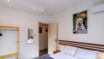Una habitación de hotel con una cama, cabecera de madera, un cuadro de un perro y una puerta que da a otra habitación.