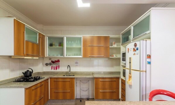 A compact kitchen with wooden cabinets, a gas stove, a sink, and a refrigerator. - Apt w/ Suite 30 m From the sea in Itapema Cae0103 (Itapema)