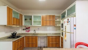 Une cuisine avec des meubles de rangement en bois, une cuisinière à gaz, un évier et un réfrigérateur.
